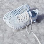 Un par de zapatillas Nike Air Force 1 blancas sobre suelo cubierto de hielo.